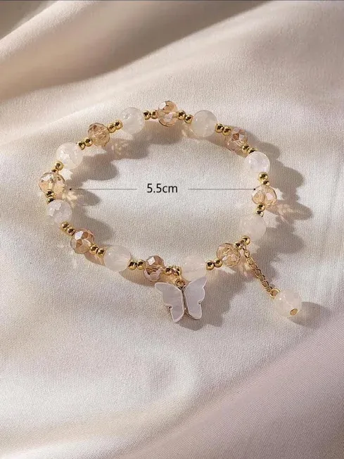 Pulsera de fantasía para dama color blanco y beige con dije de mariposa