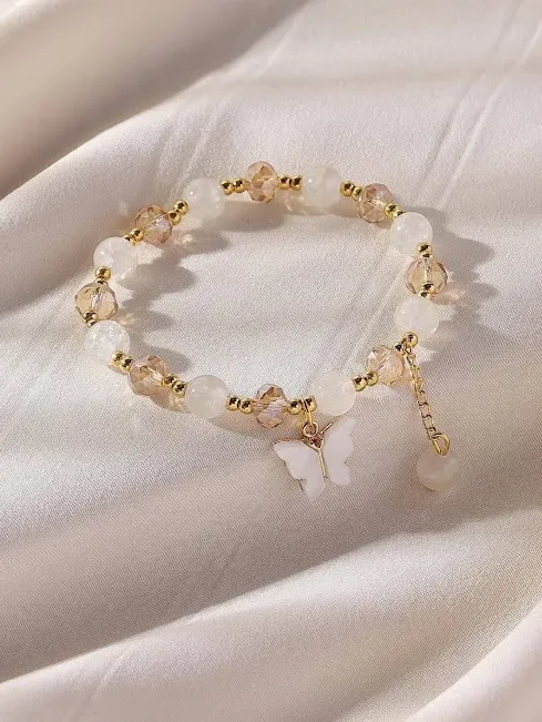 Pulsera de fantasía para dama color blanco y beige con dije de mariposa