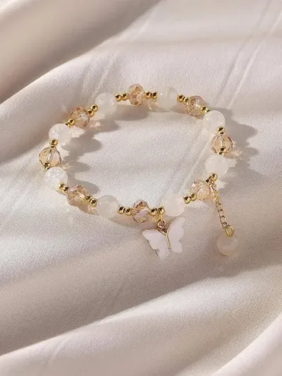 Pulsera de fantasía para dama color blanco y beige con dije de mariposa